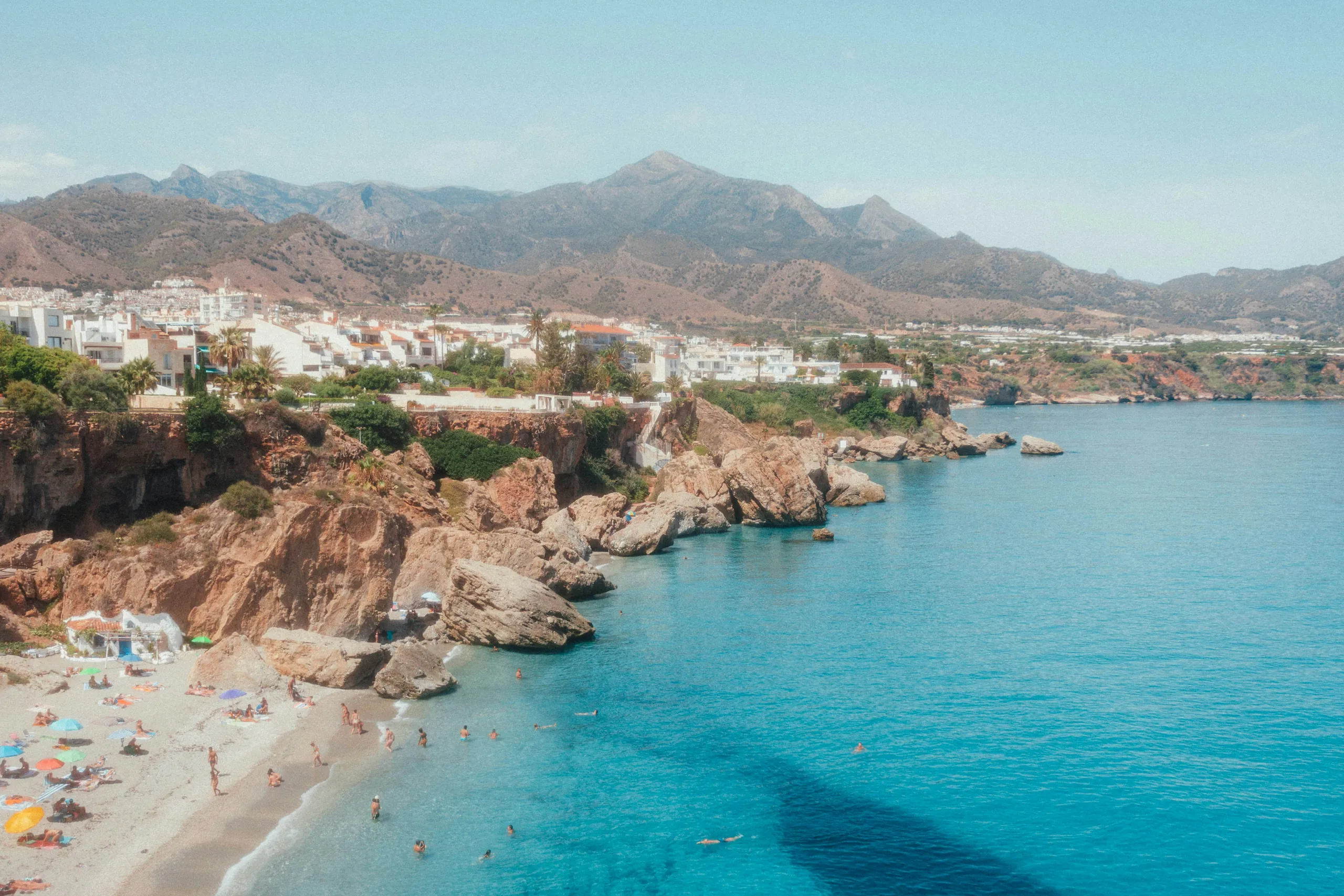 Zátoka s plavci pod bílým městem Nerja u Torroxu – Torroxu