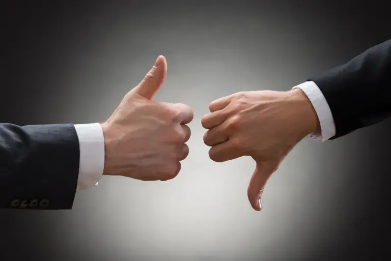 Contrasting thumbs up and thumbs down hand gestures, symbolizing customer feedback, against a gradient gray background.